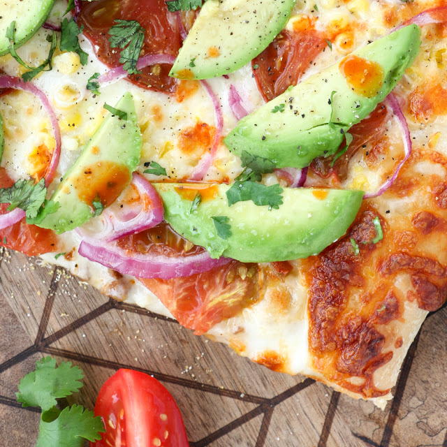 Vegetarian Roasted Corn and Avocado pizza with fresh Heirloom Tomatoes, red onion, and Cholula with an Avocado Cream Sauce - The new Cinco De Mayo Party Food Recipe